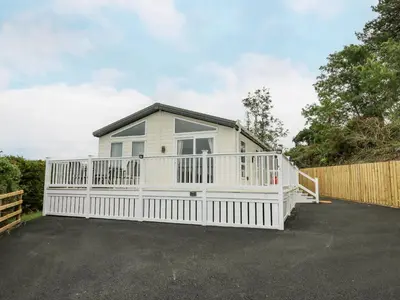 a small white house with a white fence at Platinum Lodge in Borth