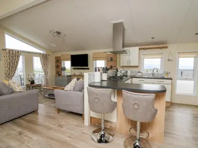a kitchen and living room with a table and chairs at Platinum Lodge in Borth