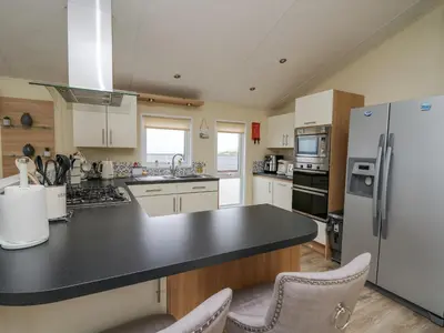 a kitchen with a black counter top and a refrigerator at Platinum Lodge in Borth