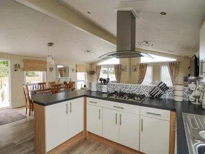 a kitchen with white cabinets and a black counter top at Platinum Lodge in Borth