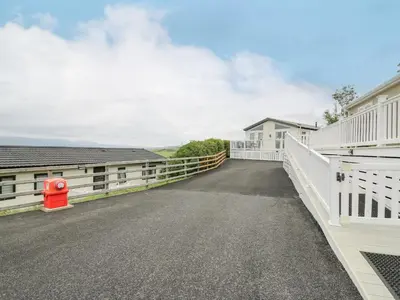 a driveway leading to a house with a white fence at Platinum Lodge in Borth