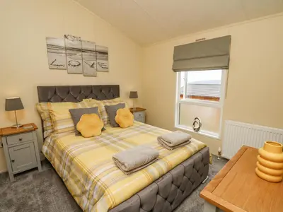 a bedroom with a bed with pillows and a window at Platinum Lodge in Borth