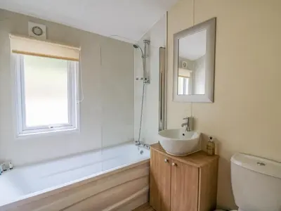 a bathroom with a tub and a sink and a mirror at Platinum Lodge in Borth