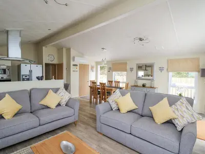 a living room with two couches and a kitchen at Platinum Lodge in Borth