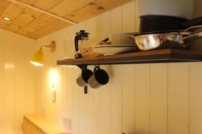 a kitchen with a shelf with pots and pans at Cosy Shepherd's Hut with Hot Tub in Church Stretton