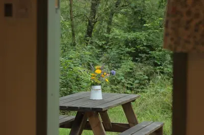 a wooden picnic table with a vase of flowers on it at Cosy Shepherd's Hut with Hot Tub in Church Stretton