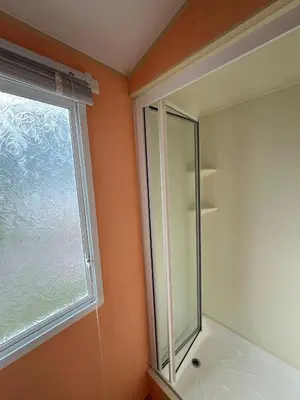 a glass shower in a bathroom with a window at Light and Airy 2 Bedroom Mobile Home in Aberystwyth