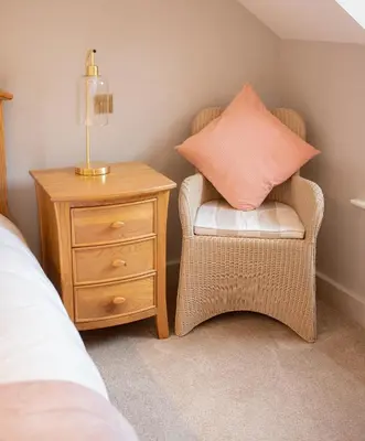 a bedroom with a chair with a pillow and a nightstand at Vineyard Country Cottage in Llanerch-Aeron