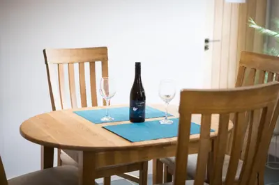 a table with a bottle of wine and two glasses at Vineyard Country Cottage in Llanerch-Aeron