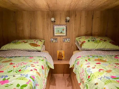 a bedroom with two beds and a wooden wall at Honeybee Home in Llansantffraid-ym-Mechain