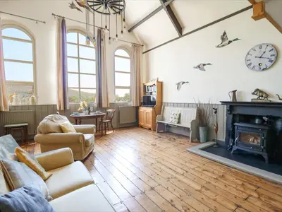 a living room with a fireplace and a clock on the wall at St Marks School House in Llanwrthwl