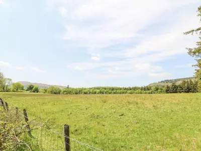 a field of green grass with a fence at St Marks School House in Llanwrthwl