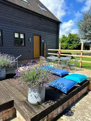 a patio with a table and blue pillows on a deck at The Caradoc in Shrewsbury