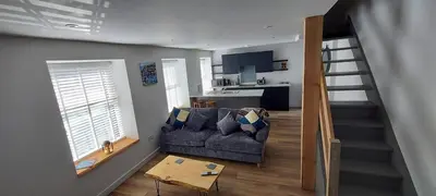 a living room with a couch and a kitchen at The Old Coach House in Aberaeron