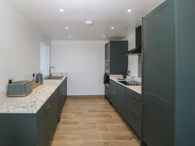 a large kitchen with blue cabinets and wooden floors at Yr Ysgubor in Dyffryn
