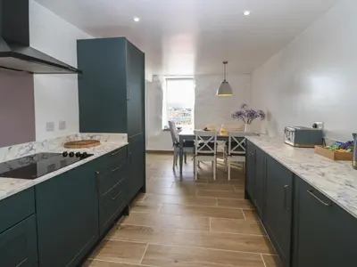 a kitchen with green cabinets and a dining room at Yr Ysgubor in Dyffryn