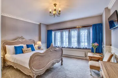 a bedroom with a large bed with blue curtains at Caer Beris Manor By Group Retreats in Builth Wells