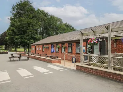a red brick building with benches and flowers on it at Heron in Leominster