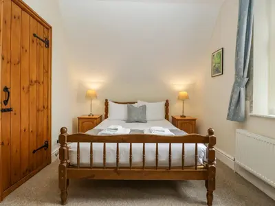 a bedroom with a wooden bed and two night stands at Keepers Cottage in Leominster