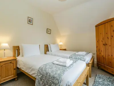 a bedroom with two beds and a wooden cabinet at Keepers Cottage in Leominster