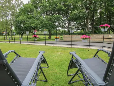 a swing set in a park with flowers at Stables Cottage in Leominster