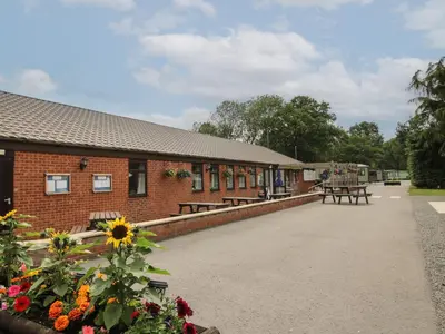 a building with benches and flowers in front of it at Stables Cottage in Leominster