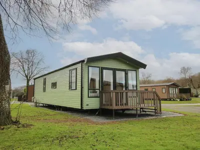 a green tiny house with a porch in a park at Owl in Leominster