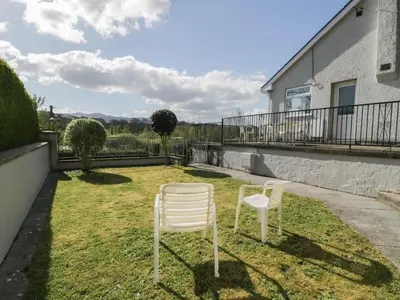 two white chairs sitting on the grass in a yard at Trem Y Foel in Penrhyndeudreath