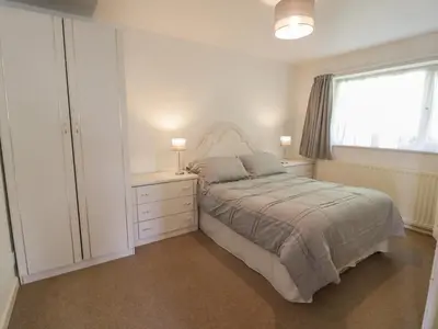 a white bedroom with a bed and a window at Trem Y Foel in Penrhyndeudreath