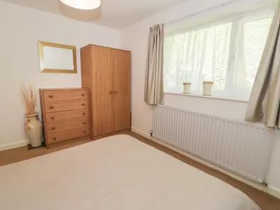 a bedroom with a bed and a dresser and a window at Trem Y Foel in Penrhyndeudreath