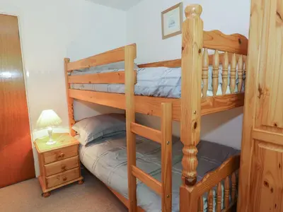 a bedroom with two bunk beds and a night stand at Trem Y Foel in Penrhyndeudreath