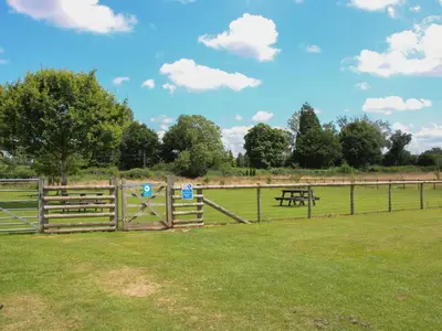 a wooden fence with a picnic table in a field at Foxglove in Leominster