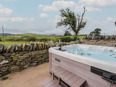a jacuzzi tub with a stone wall at Rhos Las in Derwen