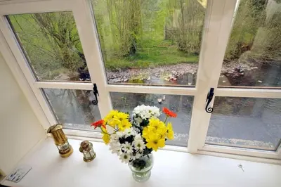 a vase of flowers sitting on a window sill at River Cottage Brecon: Hot Tub, Fire, Balcony, Wifi in Brecon