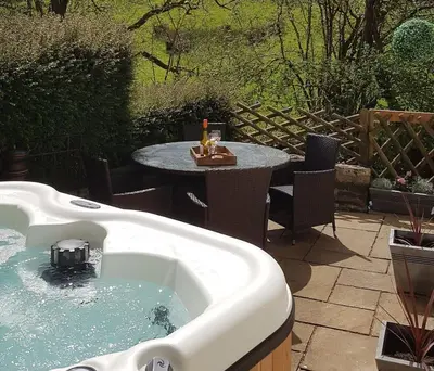 a bath tub in a yard with a table and a tableablish at River Cottage Brecon: Hot Tub, Fire, Balcony, Wifi in Brecon