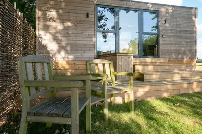 two wooden chairs sitting next to a house at Beautiful cabins in Herefordshire countryside in Hereford