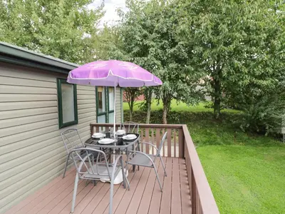 a table and chairs on a deck with an umbrella at Daisy in Leominster