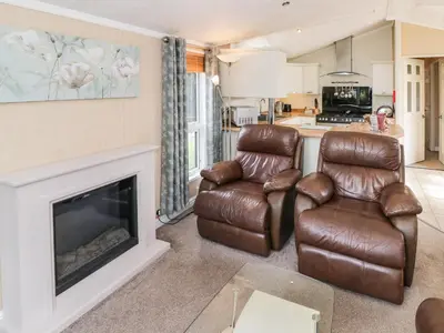 a living room with two chairs and a fireplace at Daisy in Leominster