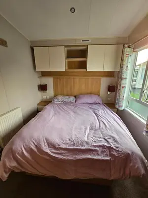 a bedroom with a large bed with purple sheets at Caravan 4 - Cambrian Coast Caravan Park in Borth