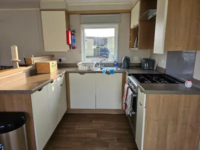 a small kitchen with white cabinets and a sink at Caravan 4 - Cambrian Coast Caravan Park in Borth
