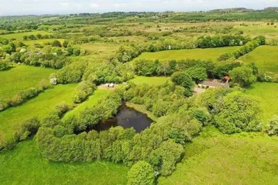 an aerial view of a field with a pond at Converted Granary on a rural small holding in Cross Inn