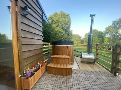 a wooden deck with a trash can and flowers at The Haystack in Oswestry