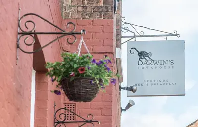 a sign on the side of a building with a basket of flowers at Darwins Townhouse in Shrewsbury