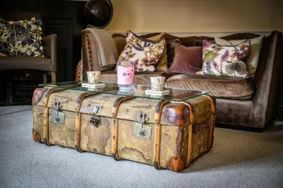 a coffee table on top of an old trunk in front of a couch at Darwins Townhouse in Shrewsbury