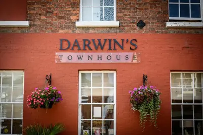 a red brick building with a sign for a dancing townhouse at Darwins Townhouse in Shrewsbury