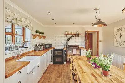 a kitchen with a wooden table and a sink at Powk Meadow Farmhouse in Leominster