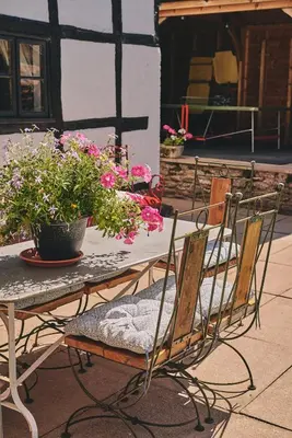 a table and chairs with flowers on a patio at Powk Meadow Farmhouse in Leominster
