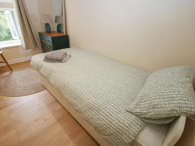 a bed with a blanket and pillows in a room at Bluebell's Cottage in Shrewsbury