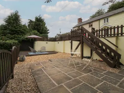 a patio with a wooden stairway next to a house at Bluebell's Cottage in Shrewsbury