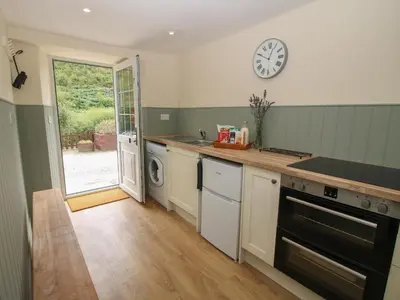 a kitchen with a sink and a clock on the wall at Bluebell's Cottage in Shrewsbury
